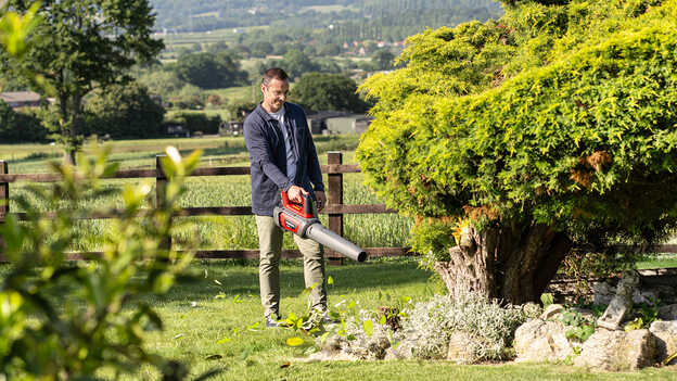 Muž drží a používa akumulátorový fukár v záhrade
