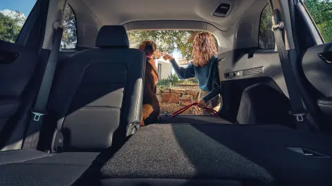 CR-V Hybrid SUV – sklopené zadné sedadlo, žena a pes v otvorenom batožinovom priestore. 