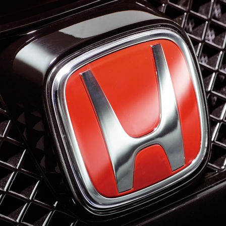Detailný záber červeného loga H značky Honda.